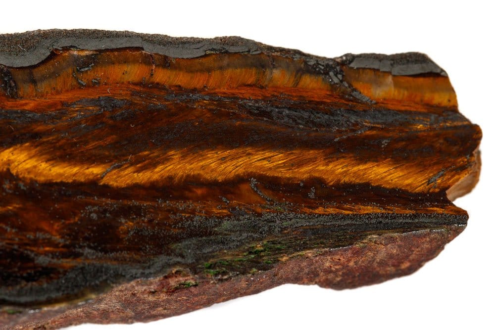 Œil de tigre brut montrant sa chatoyance dorée caractéristique — quartz fibreux issu de la transformation de la crocidolite