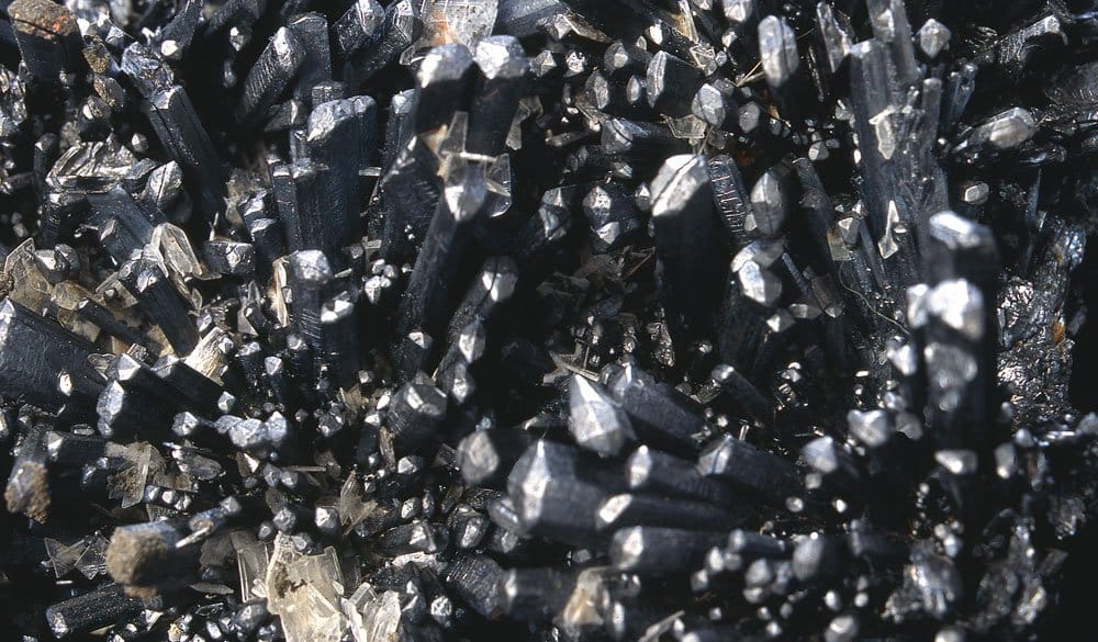 Pierre stibine cristaux prismatiques gris acier métallique en gerbes spectaculaires — histoire alchimique du sulfure d'antimoine depuis l'Égypte antique et Pline l'Ancien