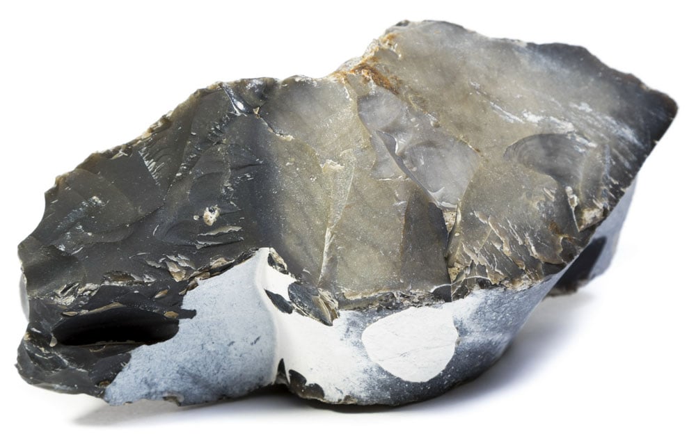 Obsidienne dorée brute montrant ses éclats pailletés dorés sur fond noir — verre volcanique formé par refroidissement rapide de lave