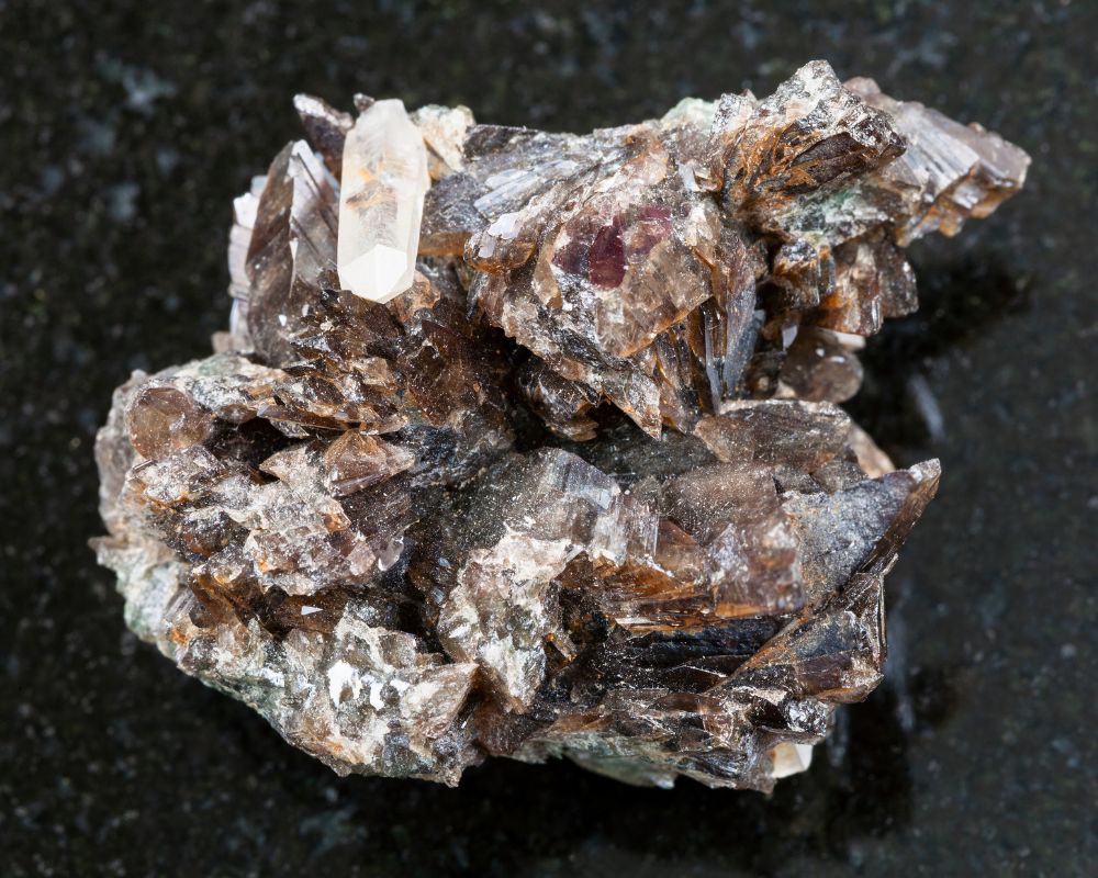 Cristaux bruts d'axinite brun-violet du Bourg-d'Oisans, montrant sa forme caractéristique en lame ou hache minéralogique