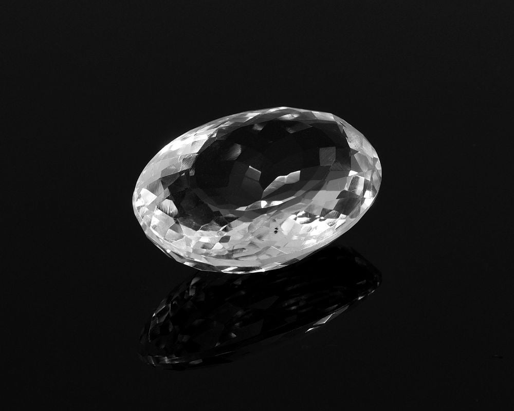 Cristal de topaze blanche aux facettes brillantes et à l'éclat vitreux pur, symbole de clarté et de transparence énergétique dans la tradition spirituelle