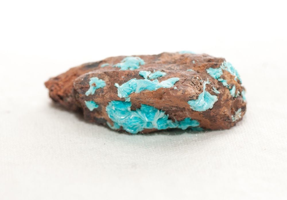 Pierre Aurichalcite brute aux teintes bleu-vert délicates illustrant son histoire depuis l'Antiquité
