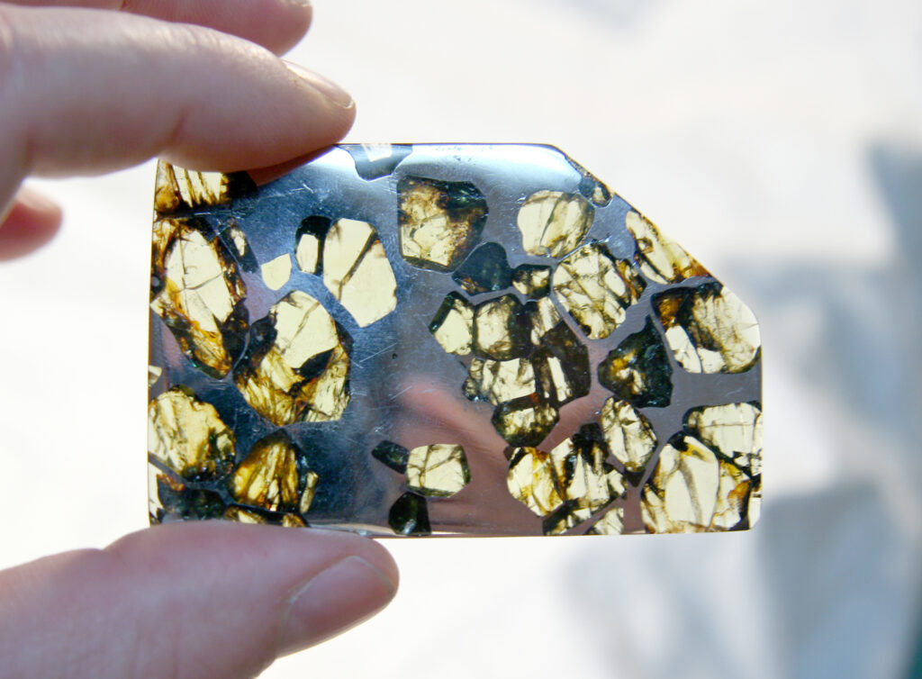 Tranche polie et rétroéclairée de la météorite pallasite d'Esquel montrant des cristaux d'olivine dans le fer-nickel