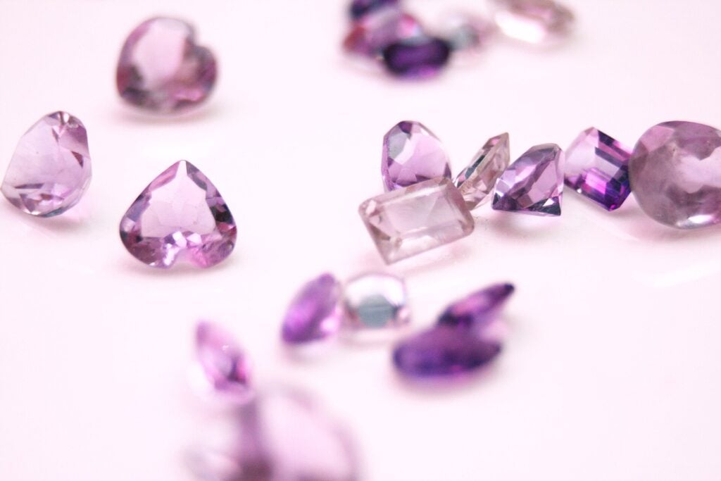 Assortiment de gemmes taillées de couleur violette, illustrant les pierres susceptibles de traitements d'embellissement