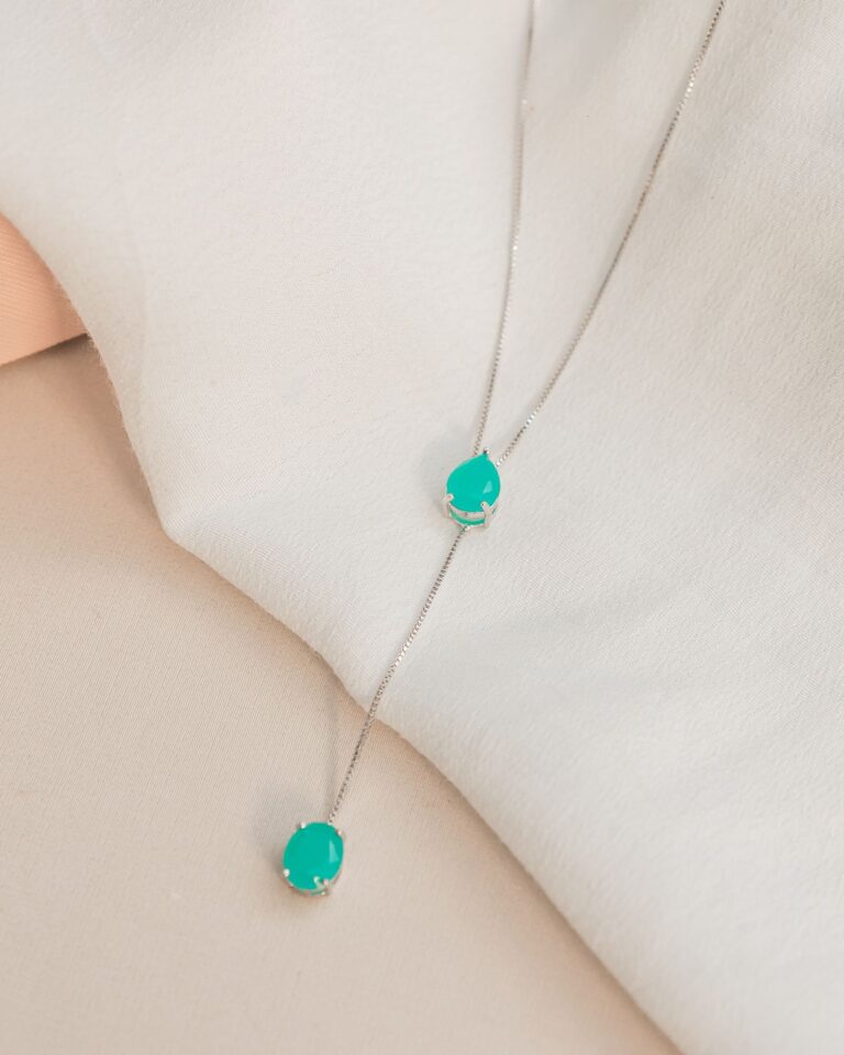 Collier en argent orné de pendentifs en turquoise posé sur un tissu clair et fluide
